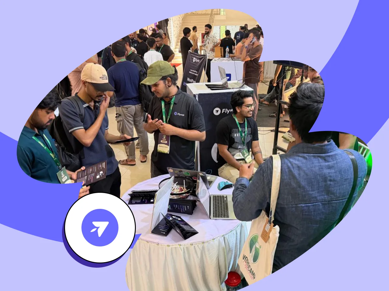 Visitors and FlyWP team members talking around the table at the FlyWP booth, with the FlyWP banner behind them